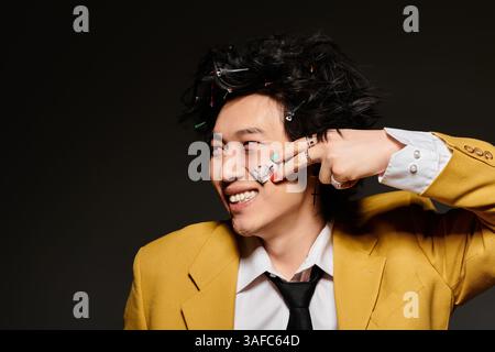 Ein modischer asiatischer Mann mit Gips auf dem Gesicht präsentiert sich mit markanter Frühlingskleidung vor einem modernen Studio-Hintergrund. Stockfoto