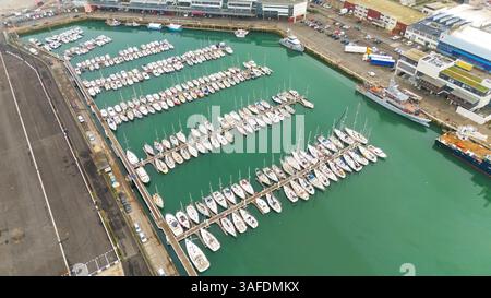 Boulogne. Frankreich 03.28.2025 Drohnenbild eines dicht gepackten Yachthafens mit Reihen angedockter Segelboote und Yachten, neben Industrie- und Gewerbegebäuden. Stockfoto