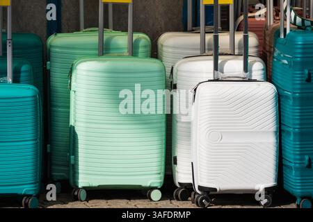 Helle Kunststoffkoffer mit Rädern in verschiedenen Farben stehen in einer Reihe, bereit für die Reise. Stockfoto