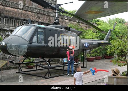 VIETNAM, Hanoi, Militärmuseum, Militärausrüstung und Kriegsschrott aus dem französischen Kolonialkrieg 1946-1954 und dem US-amerikanischen Krieg in Vietnam 1955–1975, vietnamesischer Besucher beim US-Hubschrauber Iroquois UH-1H / VIETNAM, Hanoi, Militärmuseum, Ausstellung mit Waffen zum Krieg der Amerikaner in Vietnam, vietnamesische Besucher an einem US Helikopter Stockfoto