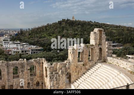 In Athen, Griechenland, das 2000 Jahre alte Odeon des Herodes Atticus mit dem Philopappos-Hügel am Horizont, gekrönt von seinem gleichnamigen Denkmal aus dem 2. Jahrhundert. Stockfoto