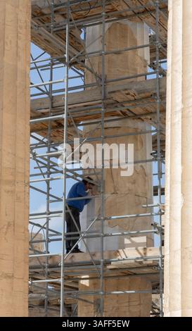 Ein Bildhauer, der auf Gerüsten steht, arbeitet an einer der Säulen des Parthenon auf der Akropolis in Athen, Griechenland. Stockfoto