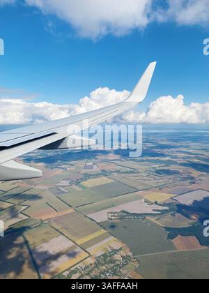 Fliegen über die Landschaft. Flugzeugflügel gegen Bauernhöfe im Hintergrund. Stockfoto