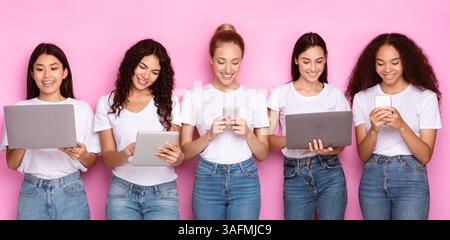 Multirassische Junge Frauen Mit Gadgets, Computer Und Smartphones, Rosa Hintergrund Stockfoto