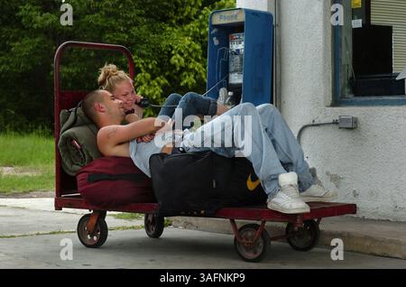 23.06.2005, BROOKSVILLE) Chris Addison (cq), 20, und Mallory Pleger (cq), 18, legen sich zurück auf ihre Taschen, während Pleger am Telefon spricht, während er auf den Bus wartet. Das Verlobte Paar war auf dem Weg nach Jacksonville, N.C., um eine Weile bei der Familie zu bleiben. Die Greyhound-Bushaltestelle in Brooksville ist in der vergangenen Woche nicht mehr geschlossen worden, wie viele andere kleine Stadtdepots im Bundesstaat, aber sie wurde auf vier tägliche Haltestellen verkürzt. Die Tankstelle, die von einer alten Tankstelle am westlichen Stadtrand aus betrieben wird, gehört und wird von Rhoda Moneyhan betrieben (Credit Image: St Petersburg Times/ZUMAPRESS.com) Stockfoto