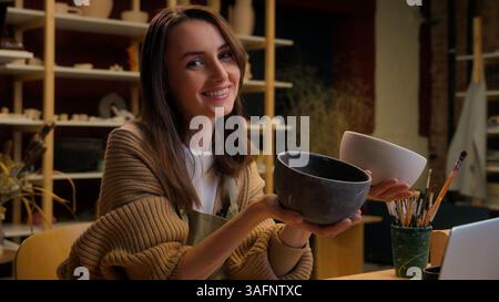 Female business owner saleswoman seller girl Caucasian woman potter craftswoman artist designer painter holding pots clay bowls craft painting Stockfoto