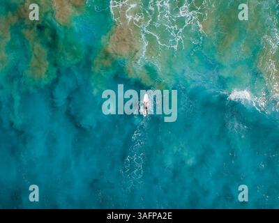 Aus der Vogelperspektive auf das faszinierende türkisfarbene Wasser und die zerklüfteten Klippen von El Nido, Palawan, Philippinen, mit ruhiger Bootsaktivität inmitten atemberaubender Atmosphäre Stockfoto