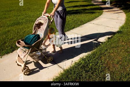 BILDUNTERSCHRIFT: (22.08.2006, INVERNESS) der 13 Monate alte Petr (cq) Bala hilft seiner Mutter Bambi Bala, einen Kinderwagen auf einem Bürgersteig im Liberty Park in Inverness zu schieben Dienstag (22.08.2006) Morgen. Petrs Mutter sagte, dass das Kleinkind seit etwas mehr als einem Monat läuft und dass die beiden in den Park kommen, nachdem sie Petrs ältere Schwester in der Schule abgesetzt haben. Sie sagte, sie genießt ihre Morgenspaziergänge, vor allem, weil sie nicht zu Hause war, um ihren Sohn zu sehen, der seine ersten Schritte macht. Glücklicherweise hatte Petrs Babysitter ein Videotelefon und nahm das große Ereignis auf. Jetzt warten wir nur auf den Adapter, damit wir ihn bekommen können Stockfoto