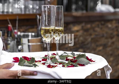 Nahaufnahme der Hände, die ein Tablett mit zwei Gläsern Champagner halten, Kellner Hände, die Tablett mit zwei Gläsern Champagner halten. Nicht erkennbare Personenhaltung Stockfoto