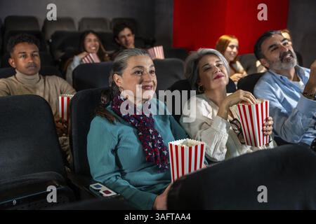 Verschiedene Gruppen von Leuten, die einen Film im Kino genießen, Popcorn essen und eine 3D-Brille tragen Stockfoto