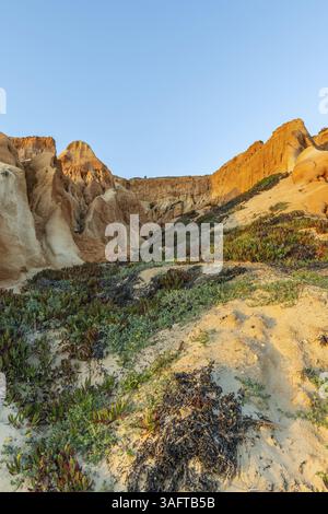 Unglaubliche Felsformationen am Atlantik. Rote Klippen aus Sand und Kieselsteinen mit erstaunlichen Formationen am Sandstrand. Ein warmer Sonnenuntergang überschwemmt die Landse Stockfoto