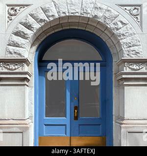 Eine raffinierte blaue Doppeltür, eingerahmt von kunstvollen Steinmetzwerken und einem geschnitzten Torbogen in Chicago Stockfoto