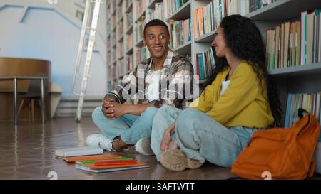 Afroamerikaner Mann Hispanic Inderin Studentinnen Klassenkameraden reden zusammen sitzen in der Bibliothek weibliche männliche kommunizieren Universitätsfreunde Stockfoto