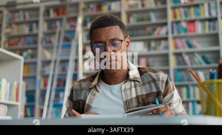 Afroamerikanischer Mann Mann männlicher Student Massage Schläfen Kopfschmerzprüfung müde Bibliothek High School Universität berührend Kopf Migräne Augen geschlossene Studie Stockfoto