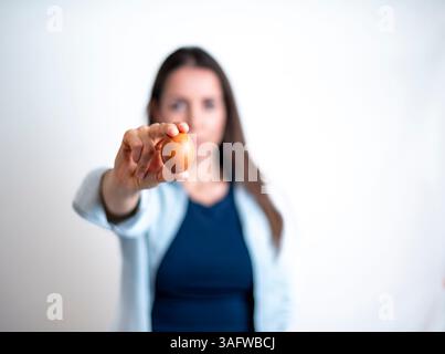 Eine Frau hält ein Ei in der Hand und zeigt darauf. Stockfoto