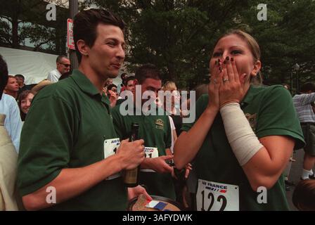 Maria Topping, 19, Kellnerin im Montgomery's Grill in Bethesda, MD, und erste weibliche Gewinnerin beim 26. Jährlichen Original Bastille Day Race and Celebration auf der Pennsylvania Avenue in Washington DC, ist erstaunt über ihren Preis - hin- und Rückfahrkarten nach Paris - den sie mit ihrer erfolgreichen Balance aus Champagner und Gläsern auf einem Tablett in 12 Blocks und zurück gewann, Freitag, den 14. Juli 2000. Ihr Freund Erdal Yucelik, 23, tobt ihren Sieg mit einer Flasche Champagner. (Bild: Washington Times/ZUMAPRESS.com) Stockfoto