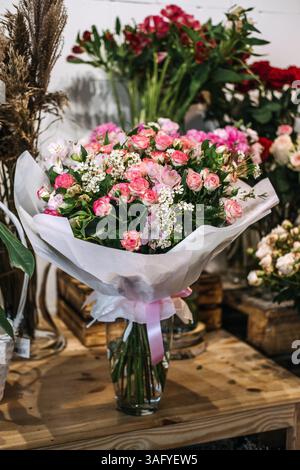 Blumenstrauß aus rosa und weißen Blumen, in Tücher und Band gewickelt, in einem Blumengeschäft ausgestellt. Florales Business Marketing, romantisches Geschenk, klein Stockfoto