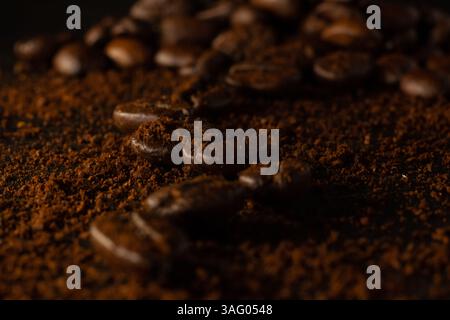 Der Weg von Kaffeebohnen auf dunklem Hintergrund. Viel Kaffee ist verstreut. Unscharfer Hintergrund. Stockfoto