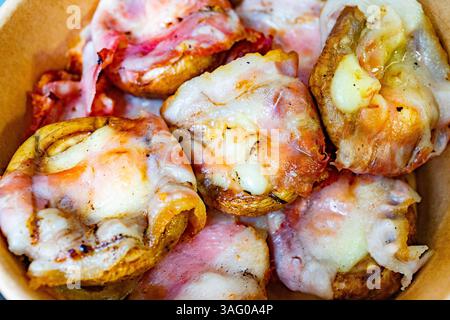 Herzhafte gebackene Pilze werden mit Käse und knusprigem Speck gefüllt, in einem Behälter angeordnet. Perfekt für einen leckeren Snack oder eine Vorspeise bei einer Versammlung oder Stockfoto
