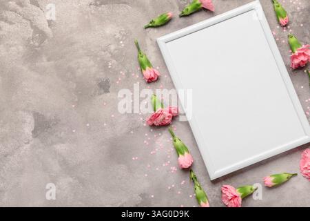 Leerer weißer Rahmen mit rosafarbenen Blumen auf grauem Marmorhintergrund Stockfoto