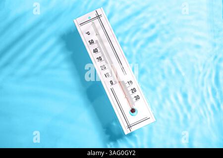 Wetterthermometer im Wasser auf farbigem Hintergrund Stockfoto