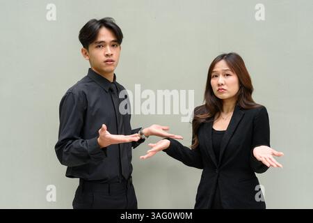 Porträt eines jungen asiatischen Paares, das Geschäftsuniform vor klarem Hintergrund trägt Stockfoto