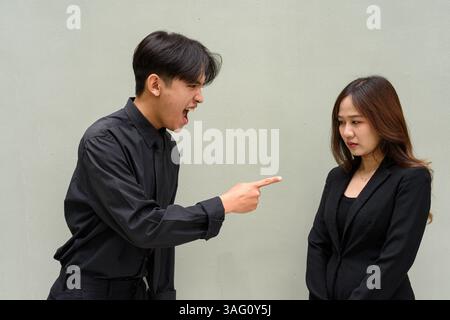 Porträt eines jungen asiatischen Paares, das Geschäftsuniform vor klarem Hintergrund trägt Stockfoto