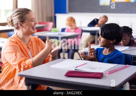 Mit Gebärdensprache, Lehrerin und Junge, die in der Schule kommunizieren Stockfoto