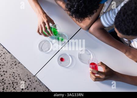 Wissenschaftliche Experimente mit bunten Flüssigkeiten und Petrischalen durchführen, Schüler in der Schule Stockfoto