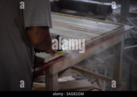 Asiatische Zimmerleute bauen Möbel oder Produkte aus Lamellen und Holz aus natürlichem Hartholz in einem Lager oder Sägewerk in einer Holzfabrik für eine Baumaßnahme Stockfoto