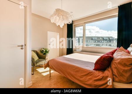 Ein stilvolles, modernes Schlafzimmer mit weicher Bettdecke, moderner Einrichtung und großen Fenstern, die viel Tageslicht in den Raum einlassen. Stockfoto