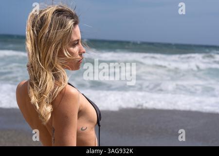 Das wunderschöne venezolanische, blonde Bikinimodell genießt die Schönheit des Alboran Sea und genießt im Urlaub ein herrliches Strandglück. Stockfoto