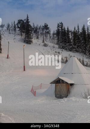 Eine kleine Hütte am Hang eines schneebedeckten Berges Stockfoto