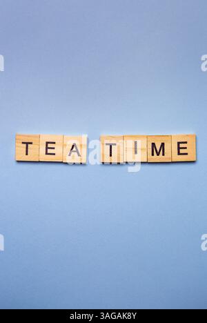 Holzblöcke beschreiben „Tea Time“ auf hellblauem Hintergrund. Stockfoto