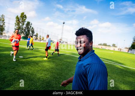 Porträt eines jungen, lächelnden schwarzen afrikaners, der während des Trainings auf einem Fußballfeld läuft und spielt, glücklich aussieht. Junger Sportler, der in einer Socce trainiert Stockfoto