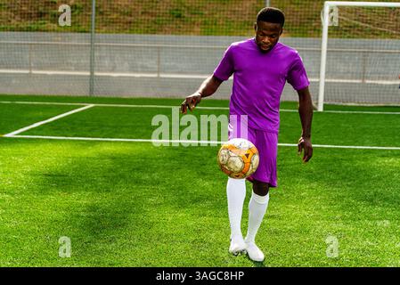 Porträt eines jungen, lächelnden schwarzen afrikaners, der während des Trainings auf einem Fußballfeld läuft und spielt, glücklich aussieht. Junger Sportler, der in einer Socce trainiert Stockfoto