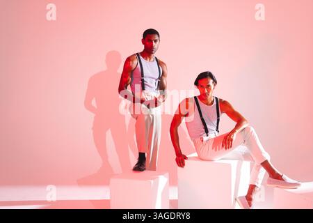 Stilvolle Männer posieren selbstbewusst in einem modernen Studio und tragen trendige Mode-Outfits. Stil, Selbstvertrauen, Garderobe, Design, Bekleidung, Eleganz Stockfoto