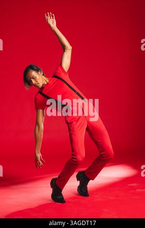 Mann in rotem Outfit auffällige dynamische Pose im Modestudio. Stil, Posen, Ausdruck, Modellierung, Kleidung, trendig Stockfoto