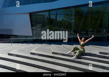 Glückliche Frau von Gen Z mit erhobenen Armen, die einen schönen Frühlingstag genießt Stockfoto