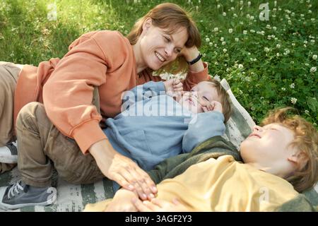 Mutter und zwei Jungs auf Blanket lächeln fröhlich Stockfoto