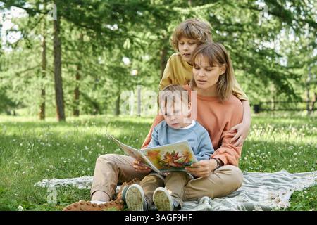 Mutter mit zwei Jungen liest Buch auf Decke Stockfoto