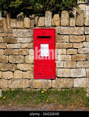 Ein roter Briefkasten, der in einer Trockenmauer im Cotswold-Dorf Edge montiert ist Stockfoto