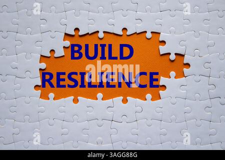 Symbol für Belastbarkeit erstellen. Weißes Puzzle mit Wörtern schafft Widerstandsfähigkeit. Wunderschöner orangefarbener Hintergrund. Business- und Build Resilience-Konzept. Kopierbereich. Stockfoto