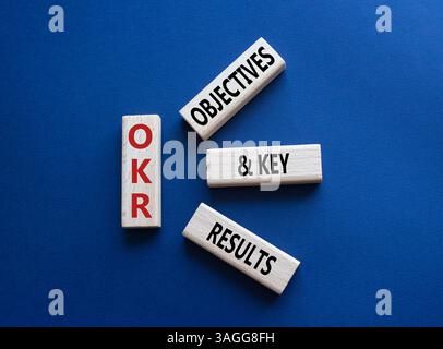 Symbol für OKR-Ziele und wichtige Ergebnisse. Holzblöcke mit den Worten OKR-Ziele und wichtige Ergebnisse. Wunderschöner tiefblauer Hintergrund. Business- und OKR-Conce Stockfoto