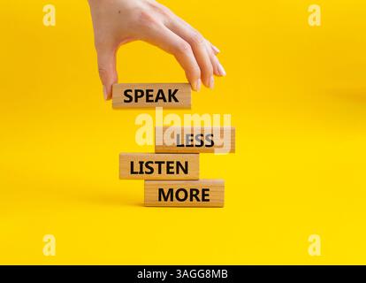 Weniger sagen, mehr hören. Holzblöcke mit Wörtern sprechen weniger Hören Sie mehr. Schöner gelber Hintergrund. Geschäftsmann Hand. Geschäftlich und weniger sprechen Stockfoto