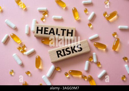 Symbol für Gesundheitsrisiken. Konzeptwort Gesundheitsrisiken auf Holzklötzen. Schöner rosafarbener Hintergrund mit Pillen. Medizin und Gesundheitsrisiko-Konzept. Kopierbereich Stockfoto
