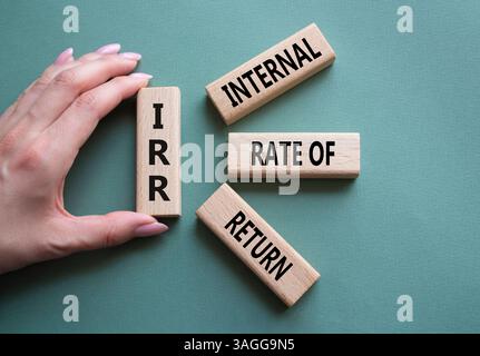 IRR - Internal Rate of Return symbol. Concept word IRR on wooden cubes. Businessman hand. Beautiful grey green background. Business and IRR concept. C Stockfoto