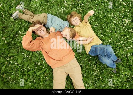 Glückliche Mutter mit zwei Söhnen, die auf Gras liegen Stockfoto