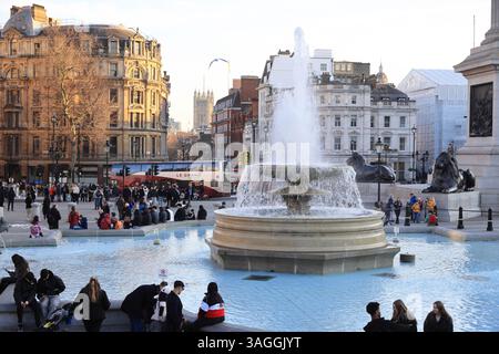 Springbrunnen am Trafalgar Square in der Wintersonne, mit den Houses of Parliament dahinter in London, Großbritannien Stockfoto
