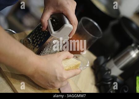 Mann Mann Mann Reibe Käse auf Holzbrett Tomatensauce für Pasta Carbonara Hausmannskost Familie italien Stockfoto
